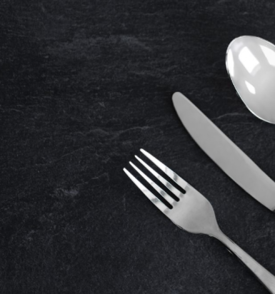 close up of fork, knife and spoon on black granite table